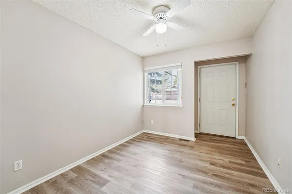 an empty room with wooden floor and ceiling fan
