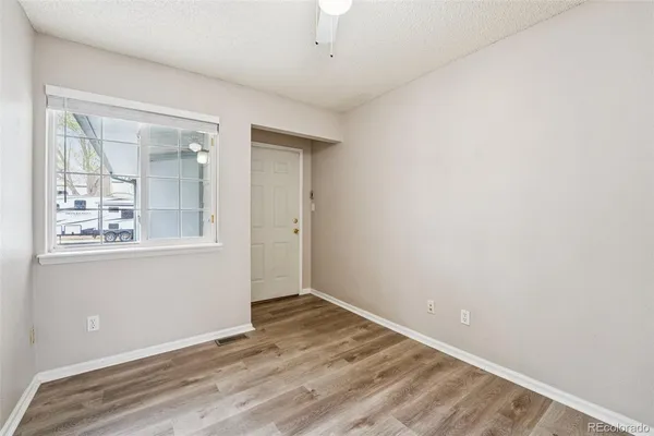 an empty room with wooden floor and windows