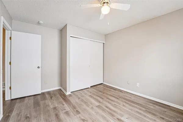 a view of a room with wooden floor and a ceiling fan