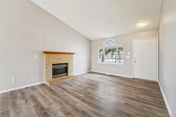 an empty room with windows fireplace and wooden floor