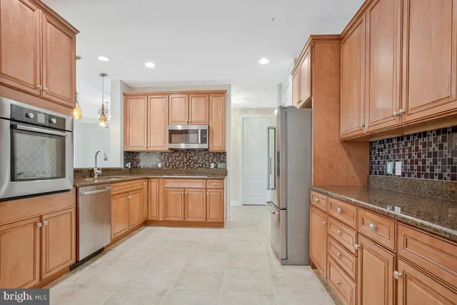 a kitchen with granite countertop a refrigerator sink and cabinets