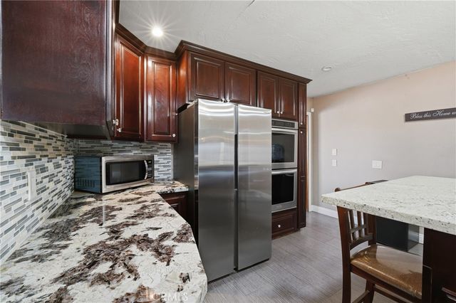 a kitchen with stainless steel appliances a stove a refrigerator and a fireplace