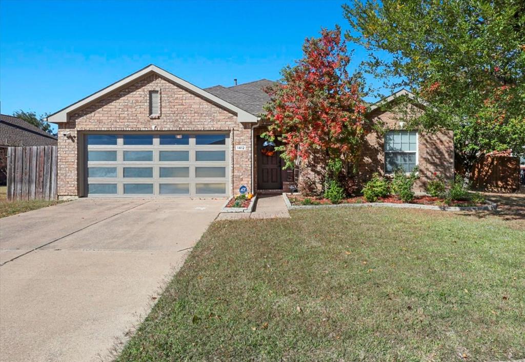 View of front facade featuring driveway, a garage, and brick siding