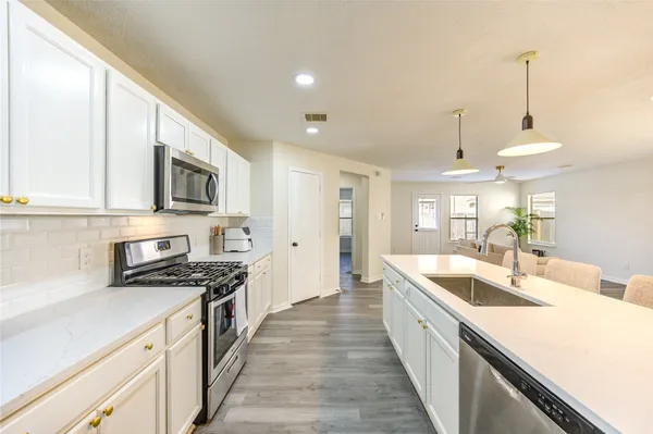 a large kitchen with stainless steel appliances granite countertop a sink a stove and a wooden floors