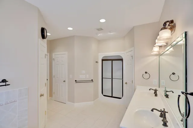 a bathroom with a granite countertop shower sink vanity and mirror