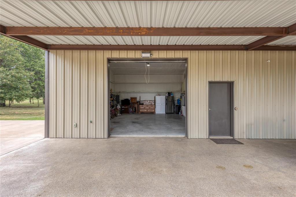 210 Spring Branch Trail North Springtown, TX 76082 - Photo 17 of 36 Metal-sided outbuilding with a large open bay, a separate entry door, and a concrete floor