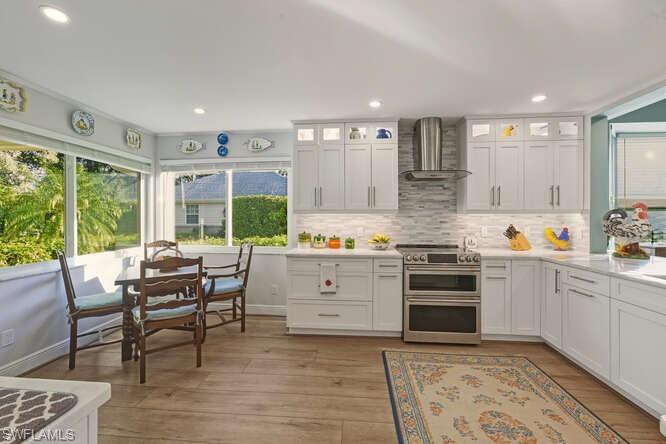 254 Edgemere Way East Naples, FL 34105 - Photo 13 of 41 Kitchen featuring glass insert cabinets, double oven range, white cabinets, wall chimney exhaust hood, and recessed lighting
