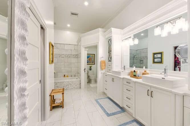 254 Edgemere Way East Naples, FL 34105 - Photo 20 of 41 Full bathroom featuring double vanity, tiled bath, a tile shower, crown molding, and light marble finish flooring