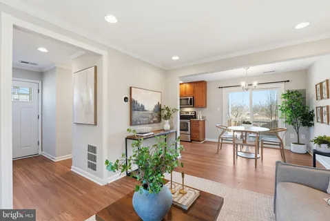 a living room with furniture potted plant and kitchen view