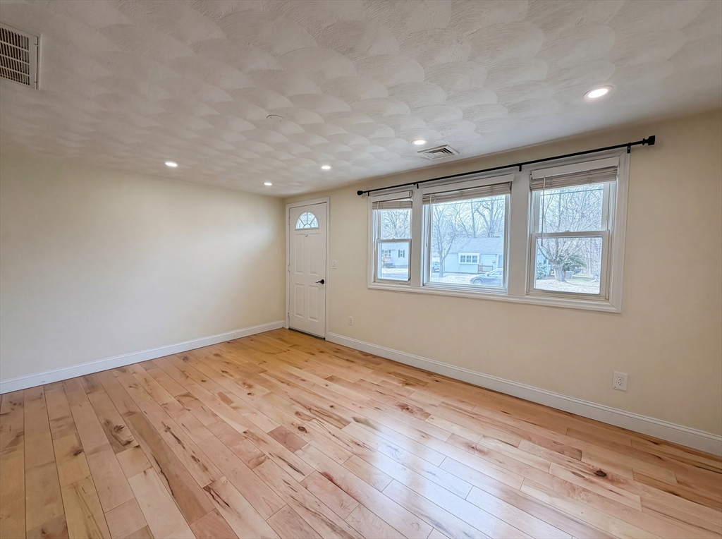 125 Burnham Road Lowell, MA 01852 - Photo 3 of 19 a view of an empty room with wooden floor and a window