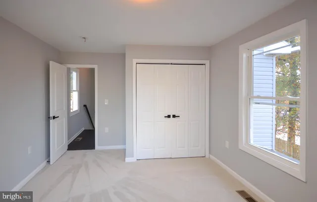 a view of an empty room with window and bathroom
