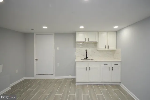 a view of kitchen with granite countertop white cabinets and sink