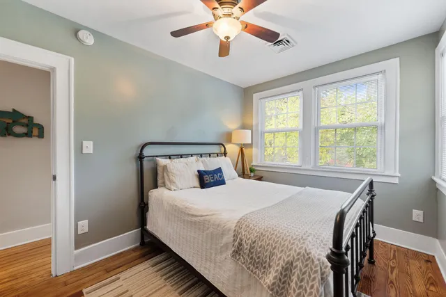 a bedroom with a bed and window with wooden floor