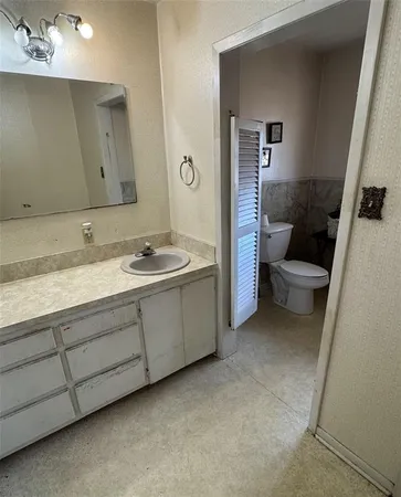 a bathroom with a granite countertop sink a toilet and a mirror