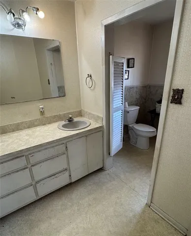 a bathroom with a granite countertop sink a toilet and a mirror