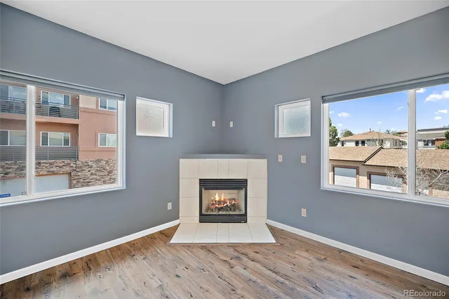 an empty room with windows fireplace and wooden floor