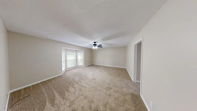an empty room with windows and ceiling fan