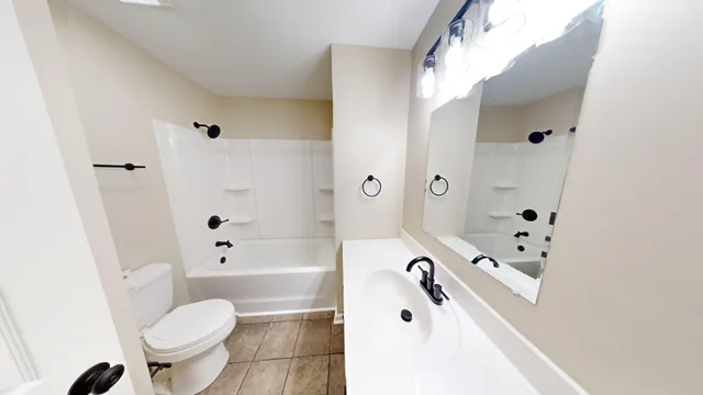 a bathroom with a bathtub sink mirror vanity and toilet