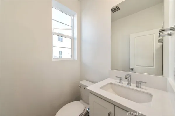 a bathroom with a toilet sink vanity and mirror