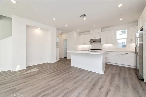 a view of kitchen with granite countertop refrigerator oven sink and white cabinets with wooden floor