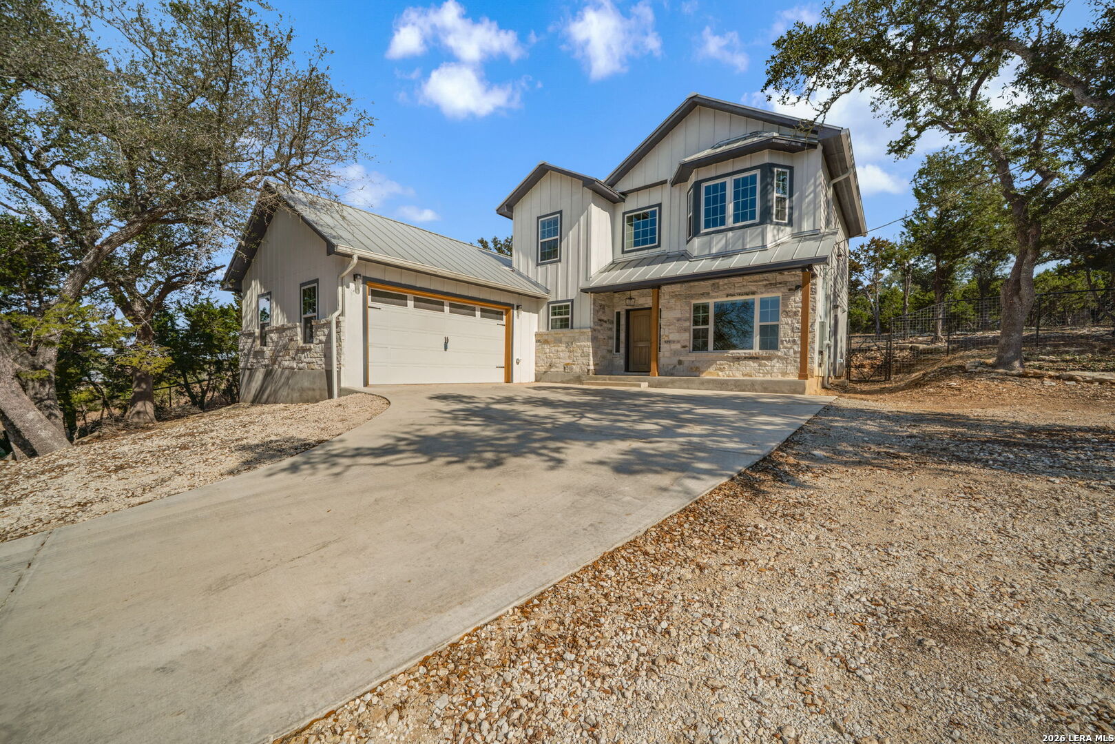 a front view of a house with a dirt yard and a large tree