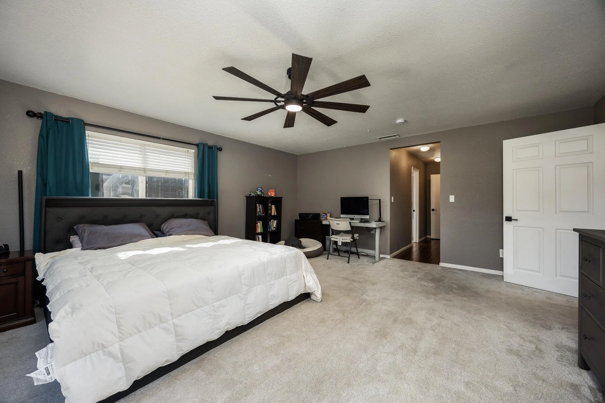 9276 Ruffin Road Santee, CA 92071 - Photo 17 of 40 a spacious bedroom with a bed a window and a chandelier