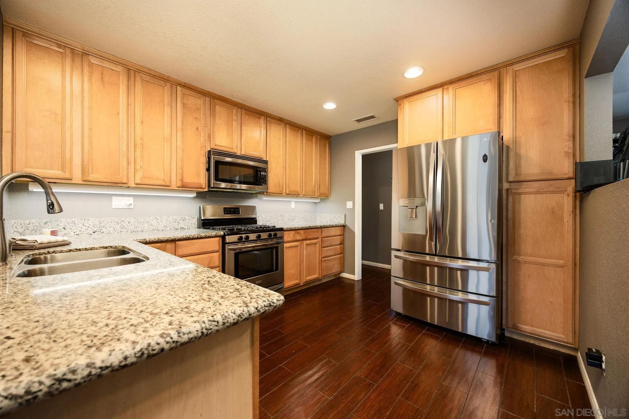 9276 Ruffin Road Santee, CA 92071 - Photo 3 of 40 a kitchen with granite countertop stainless steel appliances and wooden cabinets