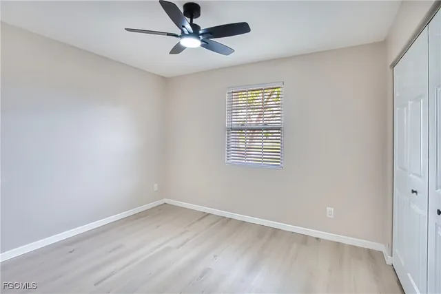an empty room with a window and ceiling fan