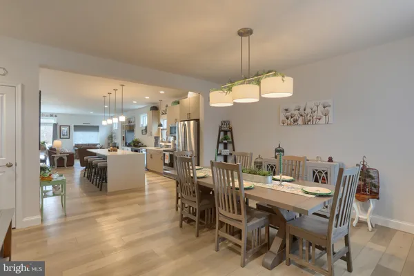 a view of a dining room and livingroom with furniture wooden floor a rug a chandelier and a mirror
