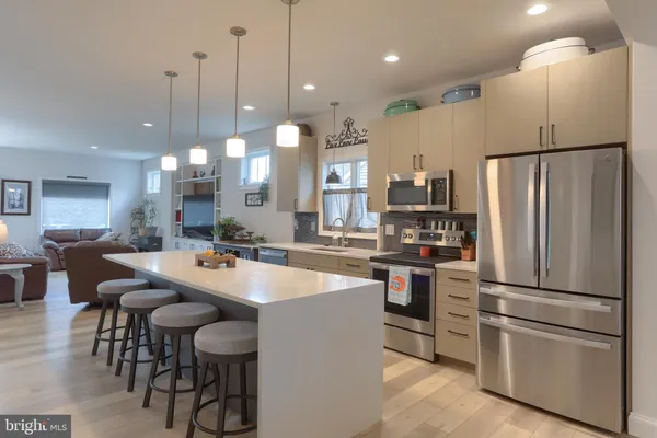 a kitchen with stainless steel appliances a refrigerator stove a sink a dining table and chairs
