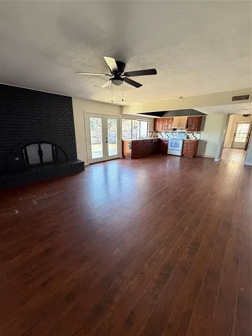 a view of a livingroom with wooden floor a ceiling fan and windows