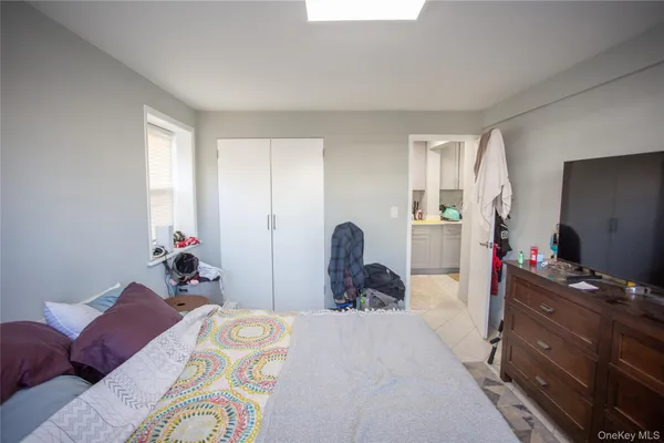 a bedroom with a bed and a flat tv screen on dresser