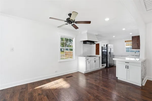 a view of a kitchen with furniture a ceiling fan and wooden floor