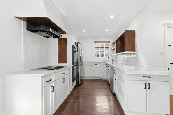 a kitchen with granite countertop a sink stainless steel appliances and white cabinets