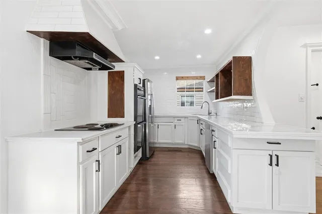 a kitchen with granite countertop a sink stainless steel appliances and white cabinets