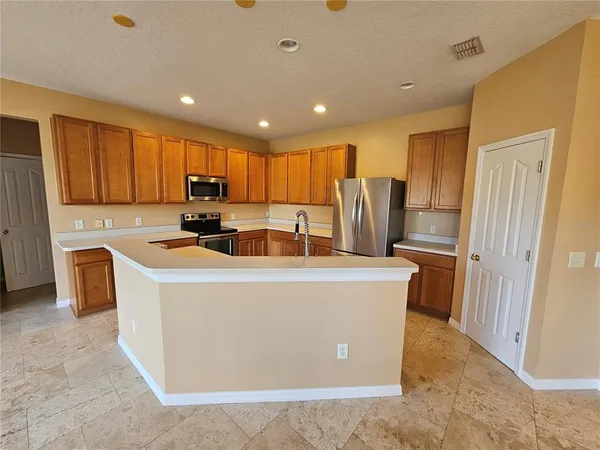 a living room with stainless steel appliances a refrigerator a sink a stove top oven a large window