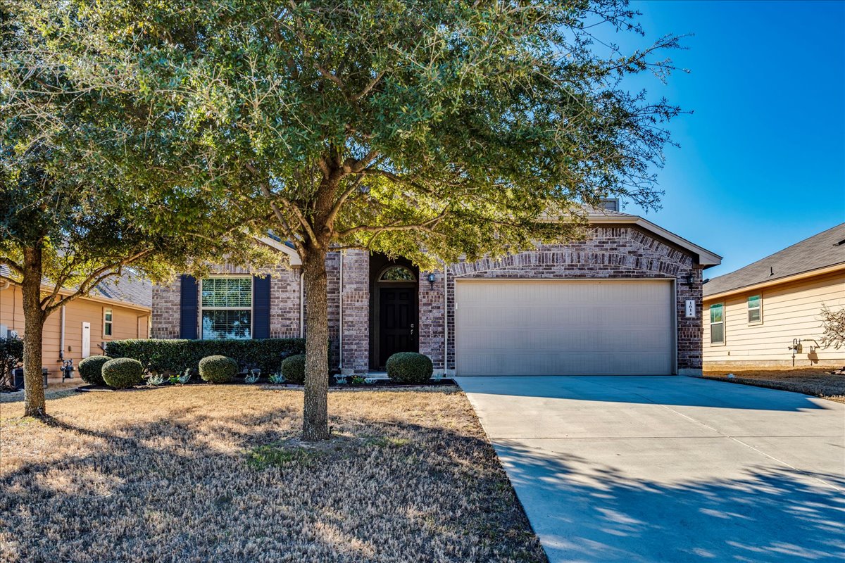 View of front of property featuring driveway, an attached garage, and brick siding
