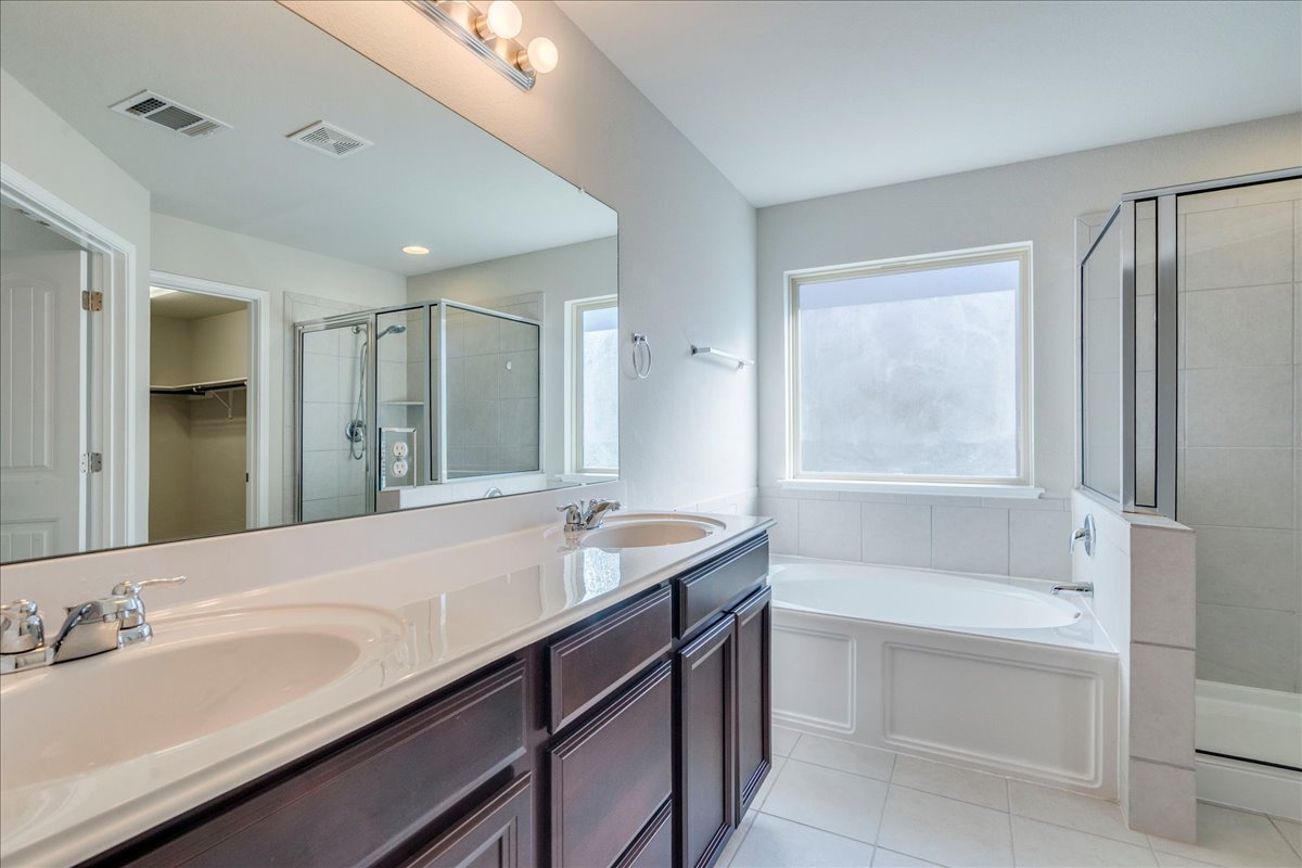 161 Mistflower Lane Kyle, TX 78640 - Photo 19 of 37 Full bathroom featuring a stall shower, a walk in closet, double vanity, a bath, and light tile patterned flooring