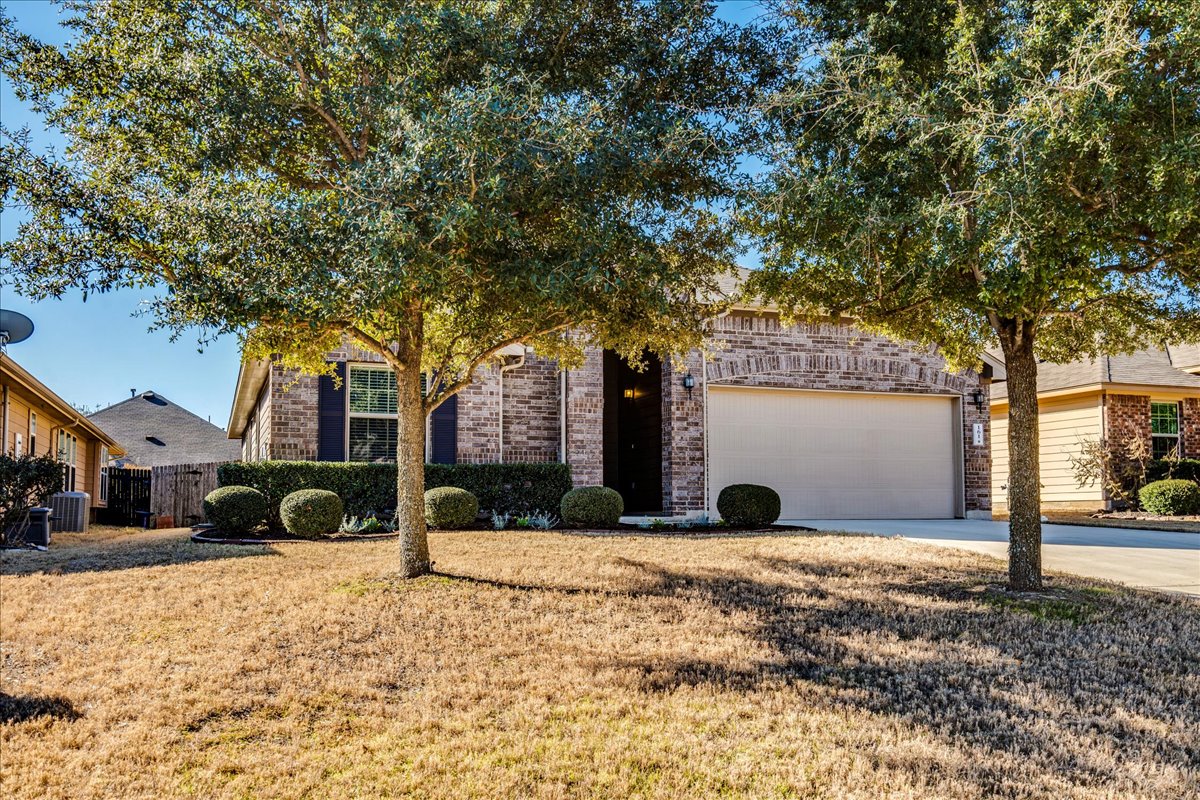 161 Mistflower Lane Kyle, TX 78640 - Photo 2 of 37 Obstructed view of property with brick siding, driveway, a front yard, and an attached garage