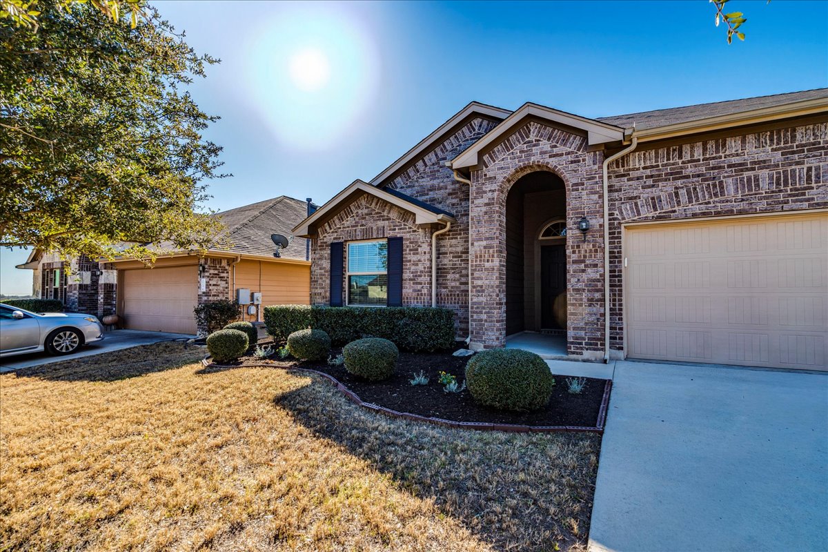 161 Mistflower Lane Kyle, TX 78640 - Photo 3 of 37 View of front facade with brick siding, a garage, concrete driveway, and a front lawn