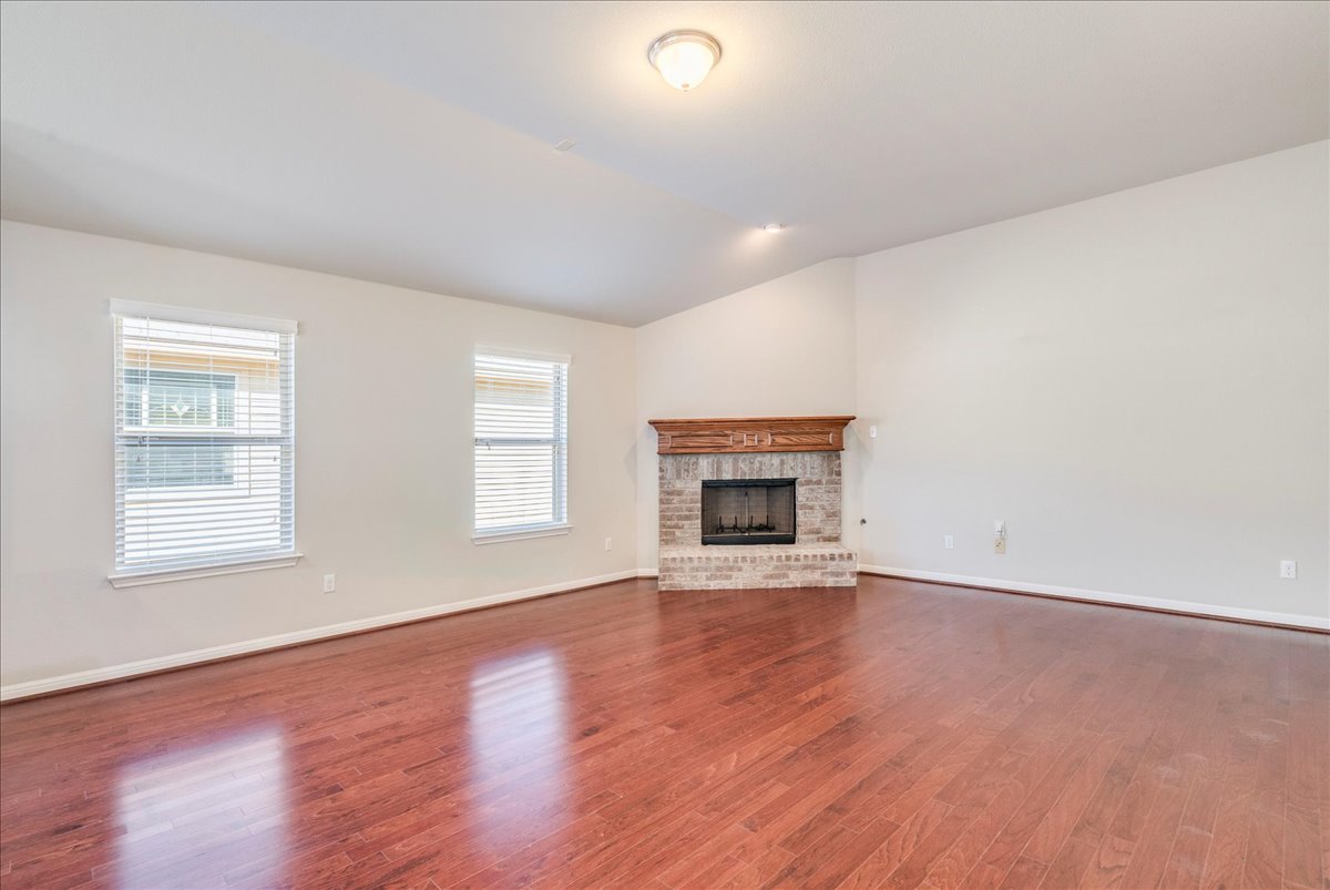 161 Mistflower Lane Kyle, TX 78640 - Photo 6 of 37 Unfurnished living room with a fireplace, lofted ceiling, and dark wood-style flooring