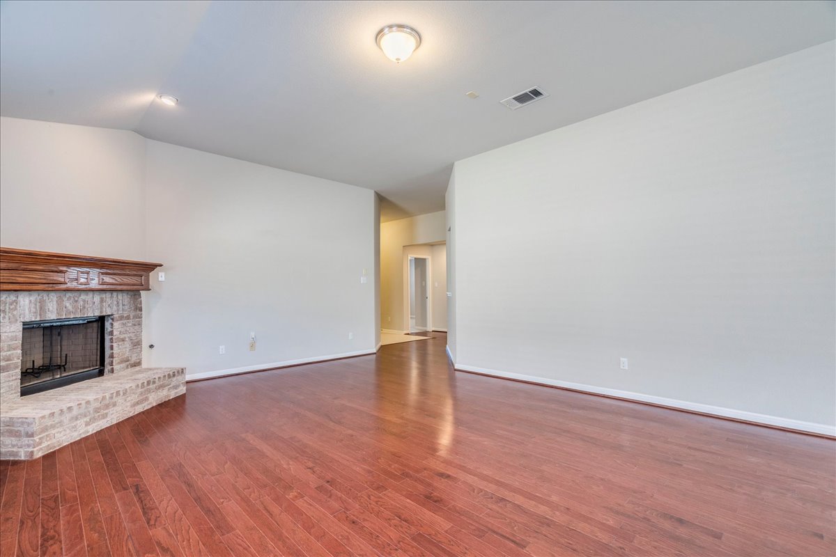 161 Mistflower Lane Kyle, TX 78640 - Photo 8 of 37 Unfurnished living room featuring dark wood finished floors, a brick fireplace, and lofted ceiling