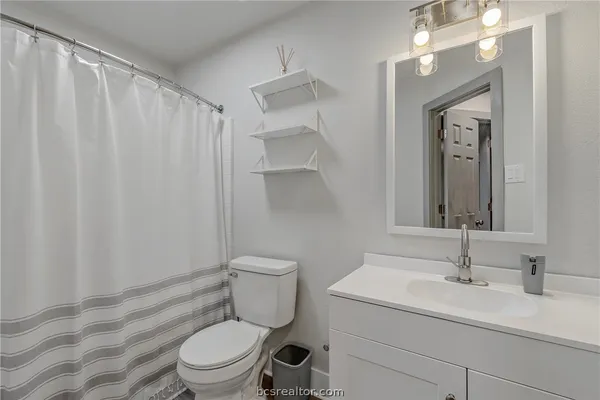 a bathroom with a toilet a sink a vanity and mirror