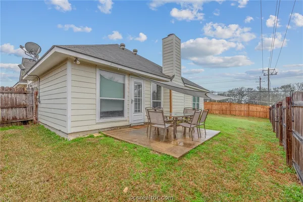 a view of a backyard with table and chairs potted plants with wooden fence