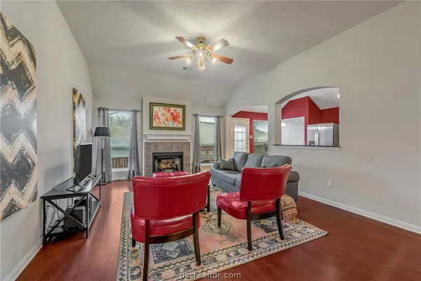 a view of a livingroom with furniture a fireplace wooden floor and a chandelier