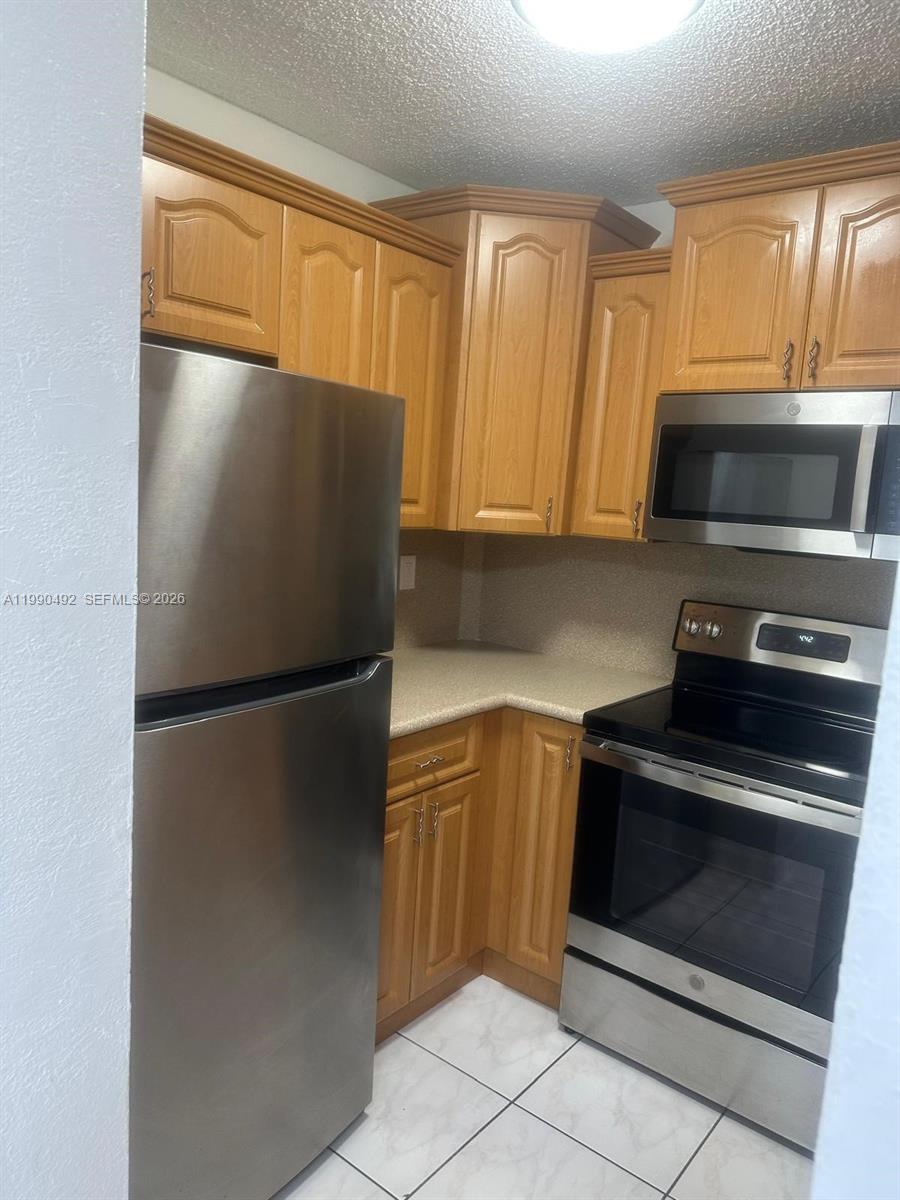 2565 West 56th Street, Unit 209 Hialeah, FL 33016 - Photo 2 of 10 a kitchen with a refrigerator and a stove top oven