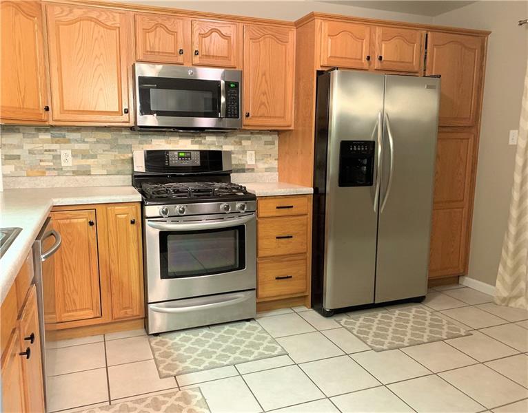212 Grace Street McKees Rocks, PA 15136 - Photo 8 of 25 Tastefully updated kitchen boasts stainless steel appliances, tile flooring, stone back splash and plenty of cabinet and counter top space.