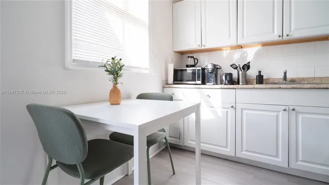 a kitchen with white cabinets and wooden floor