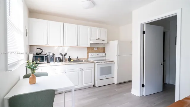 a kitchen with white cabinets and white appliances