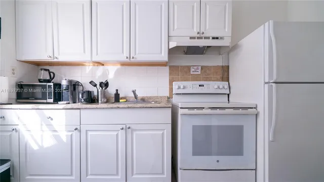 a kitchen with white cabinets and refrigerator